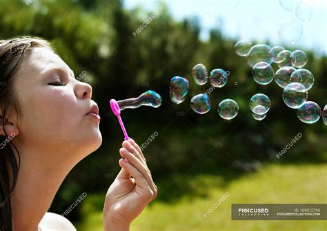 Girl blowing bubbles outdoors, focus on foreground — sunlight, nature - Stock Photo | #169012798