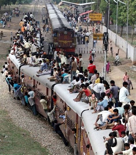 Train transportation in India -- people inside the train, hanging on the sides of the train ...