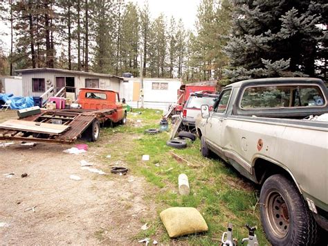 an old truck and trailer are parked in a yard next to some other junk cars