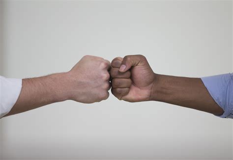 Horizontal shot of two, multi-ethnic men bumping fists. The photo is ...