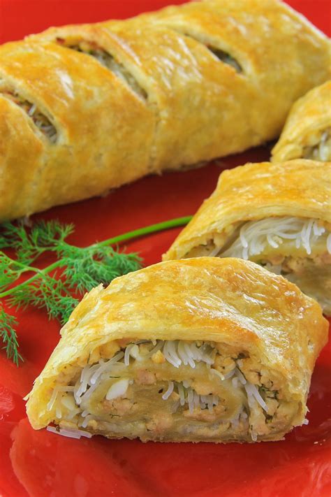 Prepared chicken puff pastry stuffed with rice noodles, eggs, dill, and ground chicken presented ...