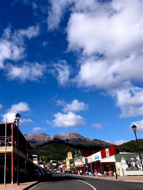 an empty street with buildings and mountains in the background