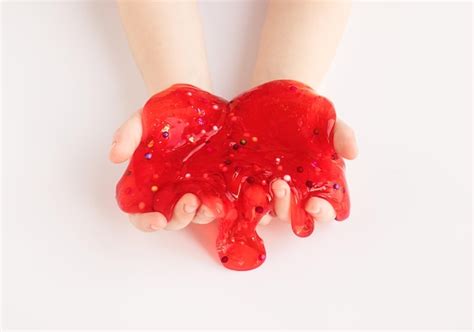 Premium Photo | Red slime toy in kids hands on white background making ...