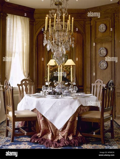 Dining room with wood panelling and table and chairs beneath ornate chandelier Stock Photo - Alamy