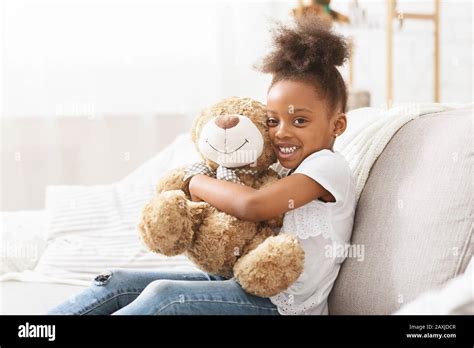 Happy black kid girl hugging teddy bear, posing at camera Stock Photo ...