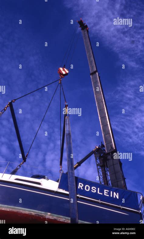 Crane lifting sailing boat out of water Stock Photo - Alamy