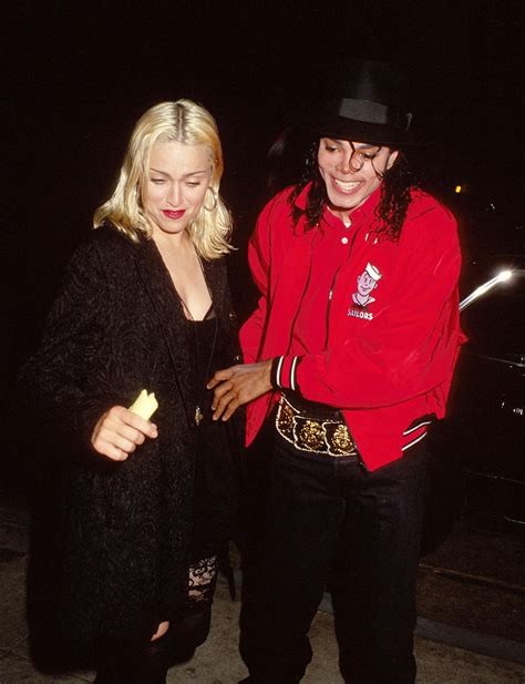 two people standing next to each other in front of a car at night with one person wearing a red ...