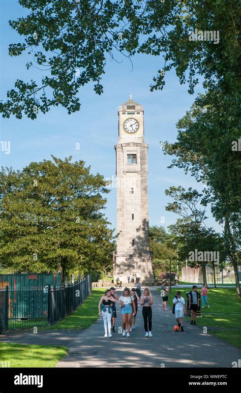 Group of young people walking in front of the Cocker Clock Tower on a sunny day in Stanley Park ...