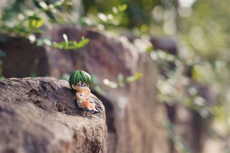 male anime character with green hair figurine on brown rock photo during daytime free image | Peakpx