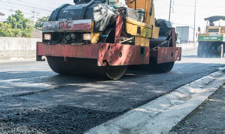 Asphalt roller working on the street that was recently repaired. The ...