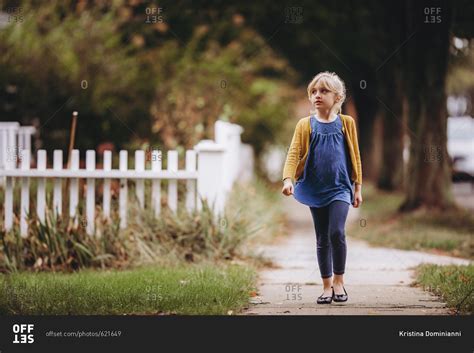 Young girl walking down the sidewalk stock photo - OFFSET