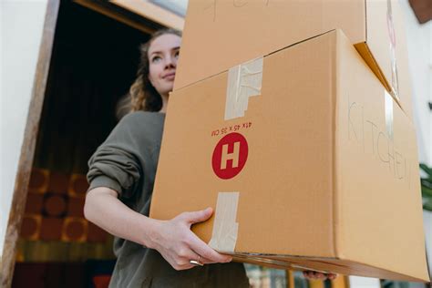 Young female carrying cardboard boxes while moving out of house · Free Stock Photo