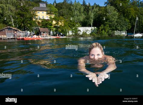 Young woman swimming in lake Starnberg, castle Unterallmannshausen in the background, Bavaria ...