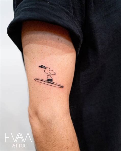 Surfer Snoopy tattooed on the upper arm