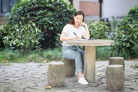 A Girl Sitting On A Bench Reading And Writing On Campus Picture And HD ...