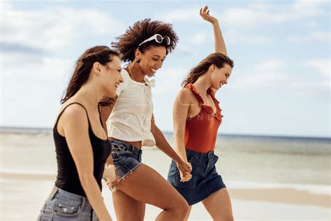 Happy friends walking on beach – Jacob Lund Photography Store- premium stock photo