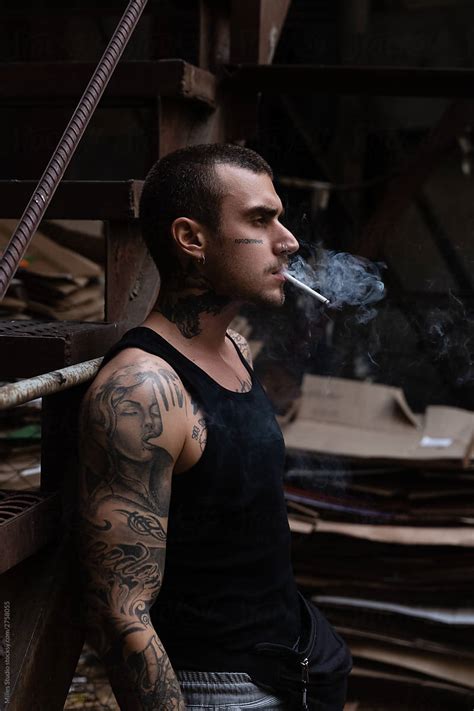 "Tattooed Man Smoking On Street" by Stocksy Contributor "Milles Studio" - Stocksy