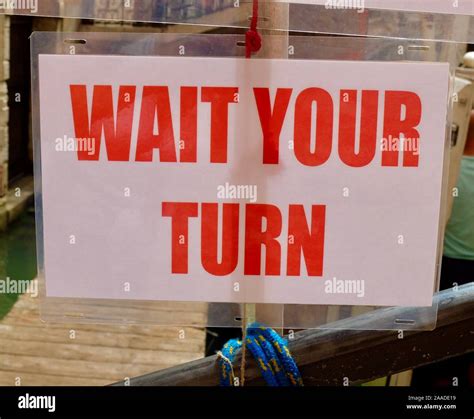 Wait Your Turn sign in red lettering Stock Photo - Alamy