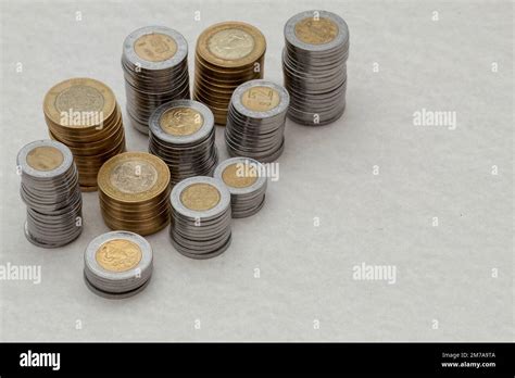 Mexican peso coins of different denominations stacked on a table with ...