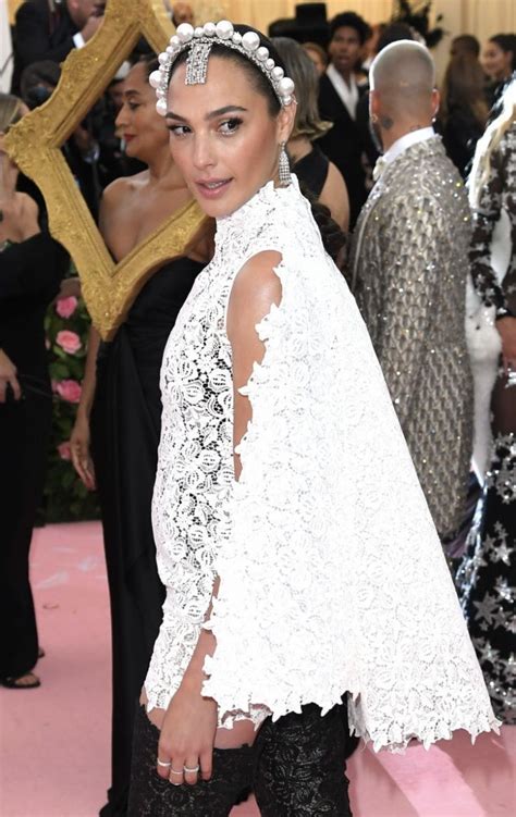 a woman in black and white outfit standing on pink carpet with other ...