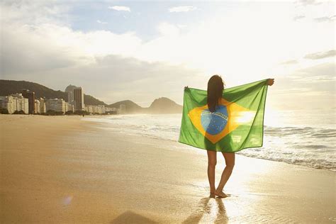 Woman holding Brazilian flag on Copacabana Beach, Rio, Brazil ...