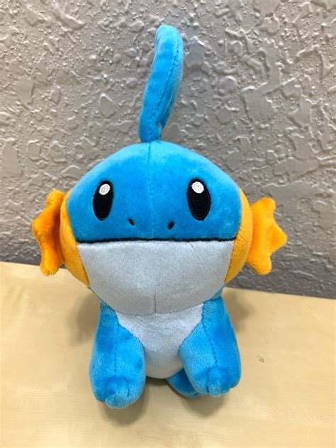 a blue stuffed animal sitting on top of a wooden table next to a white wall