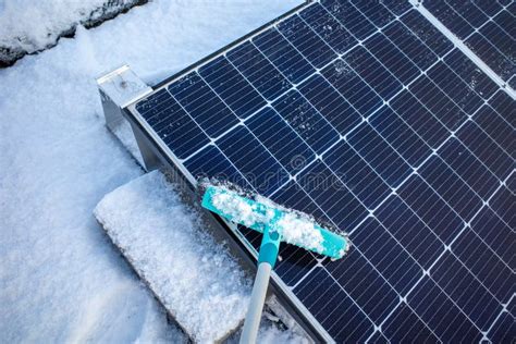 Solar Panels of a Photovoltaic System on a Roof are Cleared of Snow with a Broom Stock Photo ...