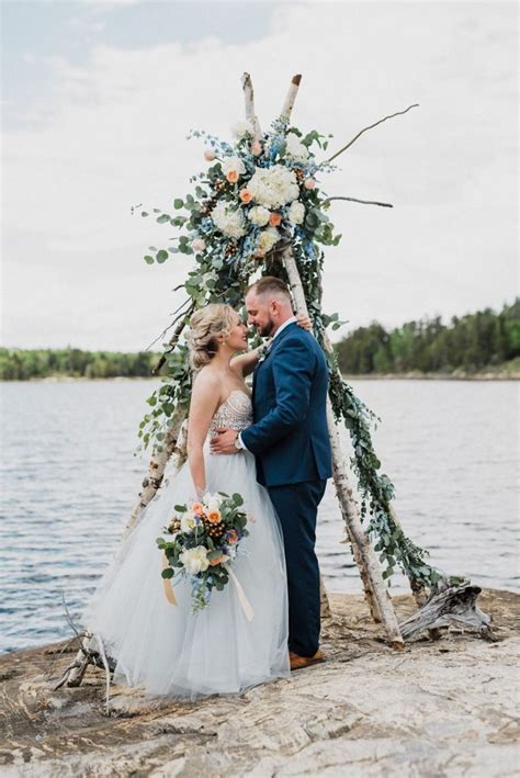 a bride and groom standing in front of an arch made out of branches with flowers