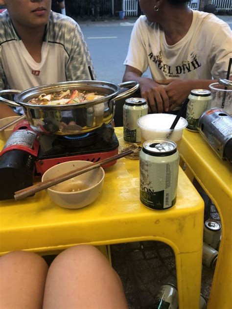 two people sitting at a yellow table with food on it and drinks in ...