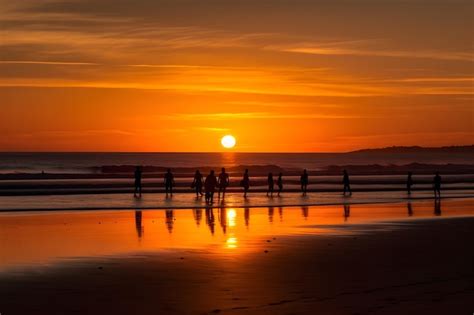 Premium Photo | People walking on the beach at sunset with the sun ...