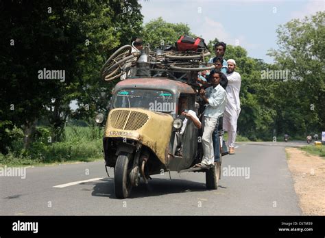 Passengers cling to the roof of a crowded vintage three wheeler Bajaj ...