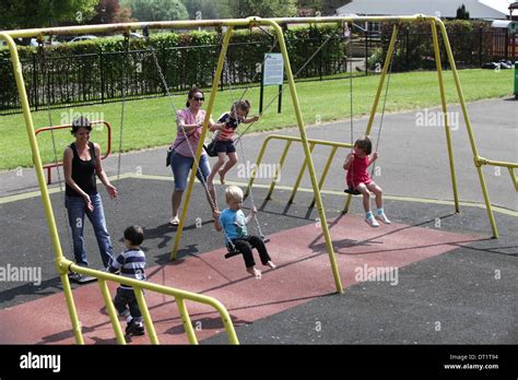 CHILDREN PLAYING ON SWINGS IN WICKSTEAD PARK IN KETTERING,NORTHANTS ...