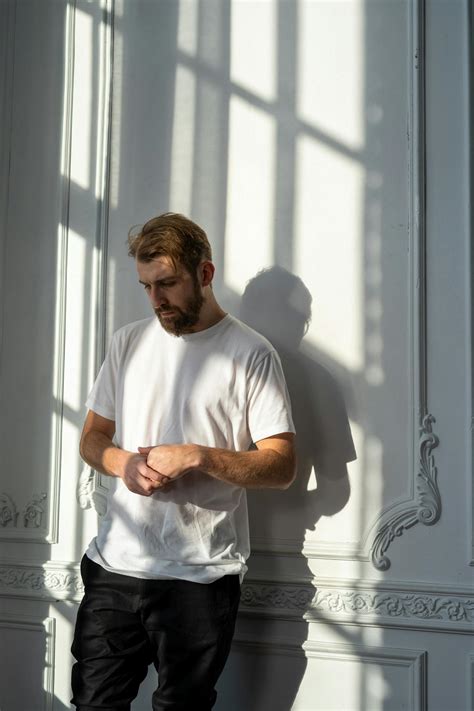 Man in White Crew Neck T-shirt Standing Beside Window · Free Stock Photo