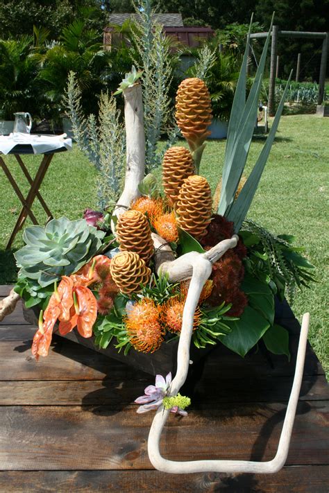 an arrangement of flowers and plants on a wooden table in the grass ...