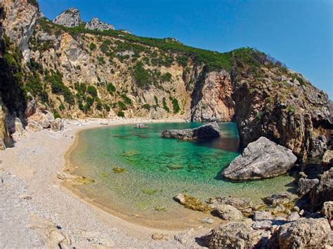 the beach is surrounded by large rocks and clear water