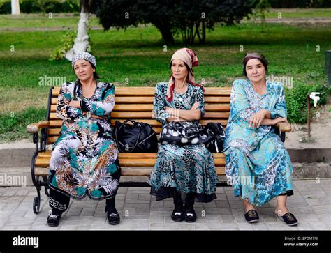 Uzbek women dressed in Uzbek dresses sitting on a bench in a park in ...