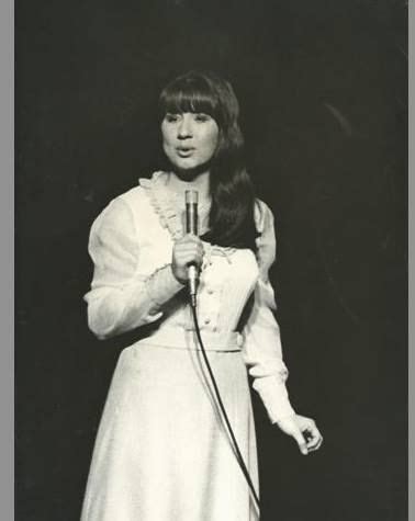 an old photo of a woman holding a microphone in her right hand and looking at the camera