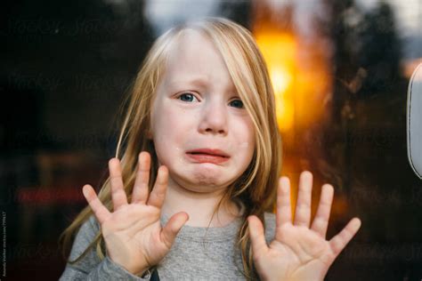 Portrait through glass of a Little Girl with a Sad Face by Amanda Voelker - Stocksy United