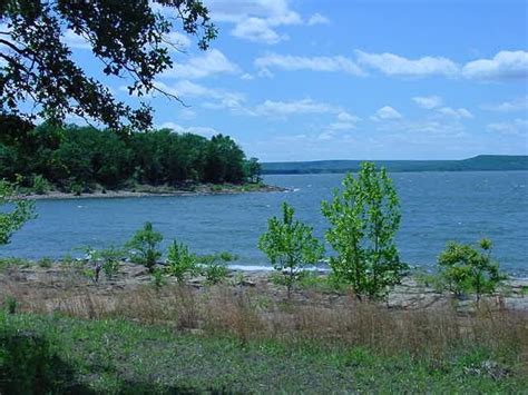 the water is calm and blue with some clouds in the sky above it on a sunny day