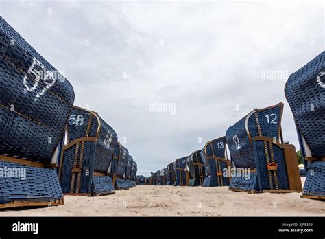 Rows of blue beach rattan huts on a beach on a cloudy day. No tourists ...