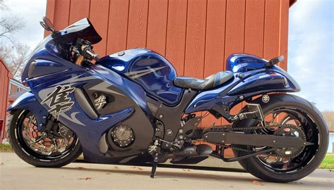 a blue motorcycle is parked in front of a red building with a brown wall behind it