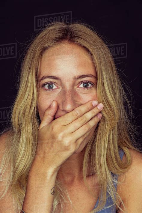 Young woman laughing with hand over mouth - Stock Photo - Dissolve