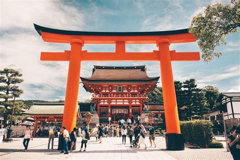 people are walking around in front of an orange tori - style structure ...