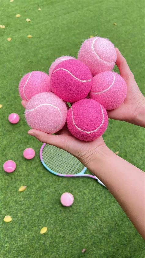 a person holding a bunch of pink tennis balls