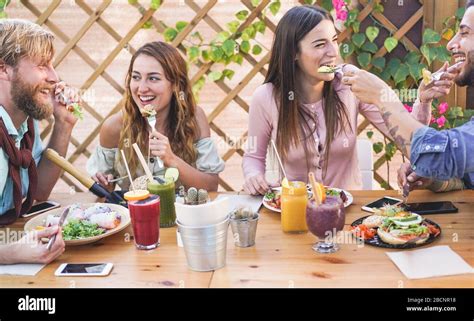 Young people eating brunch and drinking smoothies bowl with in eco bar ...