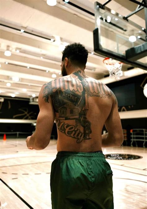 a man with tattoos on his back standing in front of a basketball hoop