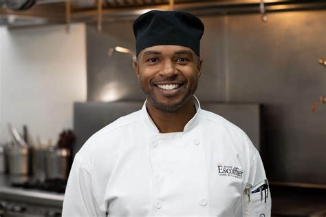 Chef in uniform posing for a photo in a kitchen