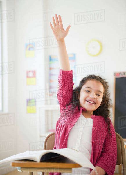 Hispanic girl raising hand in classroom - Stock Photo - Dissolve