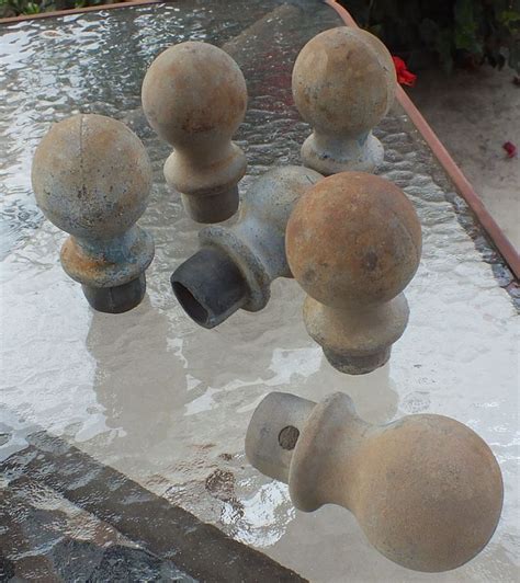 an assortment of metal objects sitting on top of a table in the water with flowers behind them