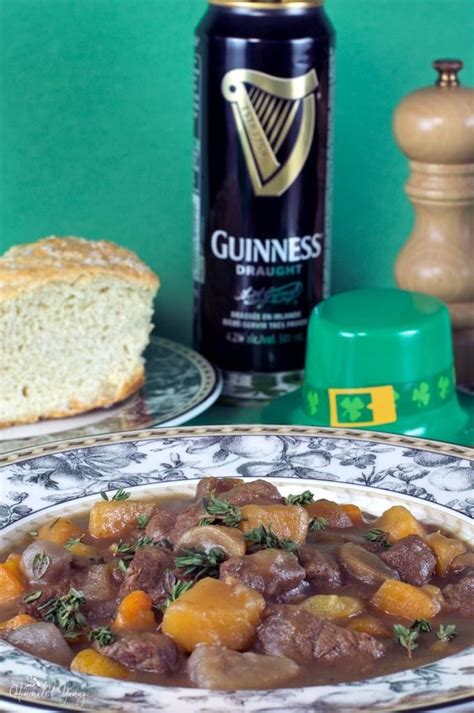a plate with meat and vegetables next to a bottle of guinness